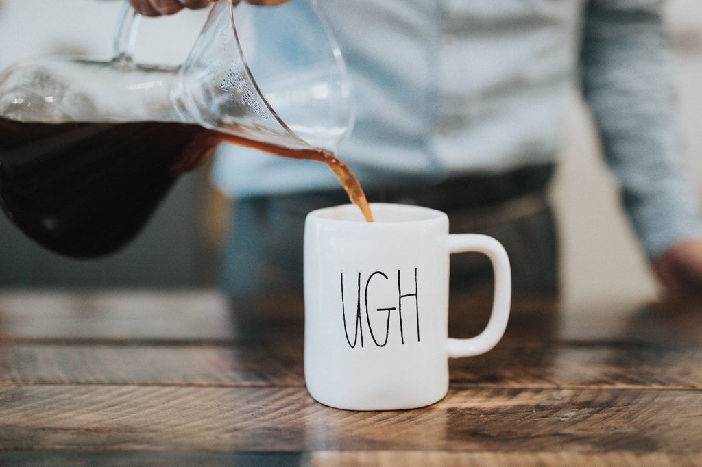 Coffee being poured into a white mug labelled UGH