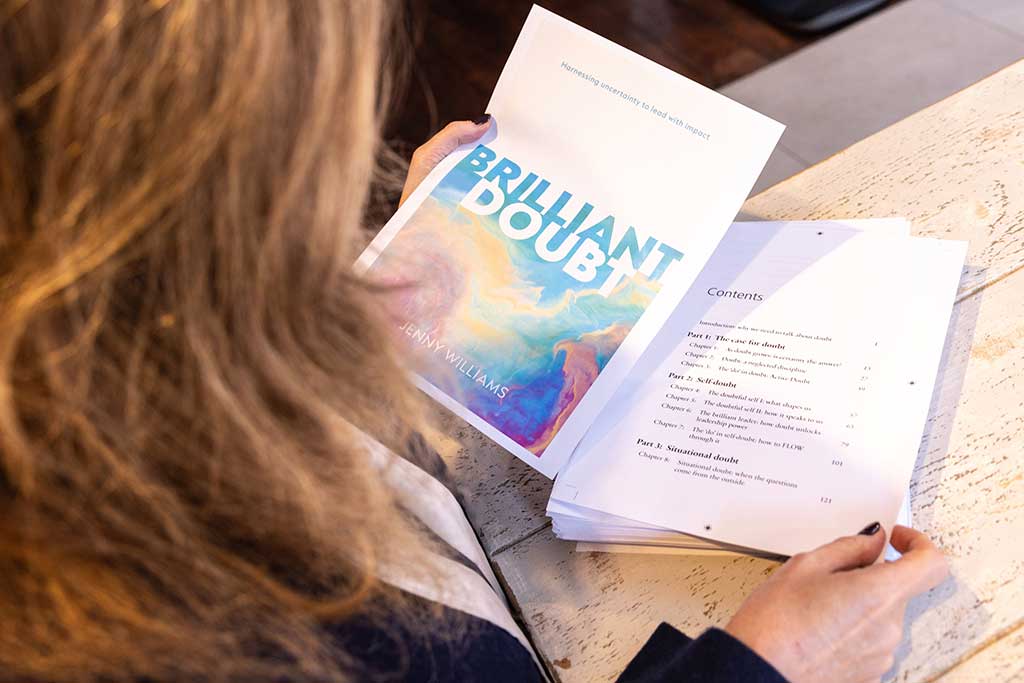 Person holding the Brilliant Doubt book open, showing the cover and contents pages, representing reflective learning and using doubt as a source of insight.